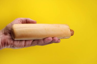 french hot dog with ketchup sauce in hand on yellow background