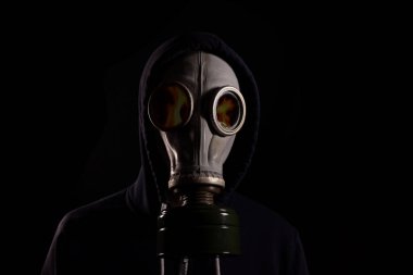 Gaz maskeli kapüşonlu ve gözlüklerinde ateş yansıması olan bir adam. Yangın kavramı..