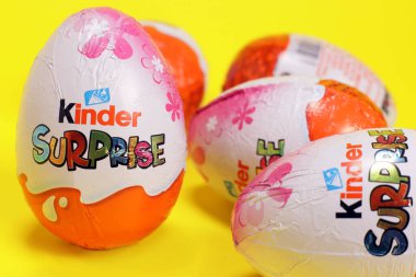 Magdalinovka, Ukrayna - 3 Mart 2023. Çikolata yumurtası Kinder Sürprizi içinde koleksiyon oyuncakları olan sarı arka planda