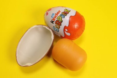 Magdalinovka, Ukrayna - 4 Mart 2023. Çikolata yumurtası Kinder sürprizi ve sarı arka planda oyuncağı olan bir kapsül.