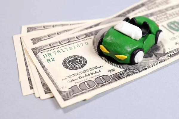 Plasticine car on dollar bills, concept of content auto insurance, repair, technical inspection
