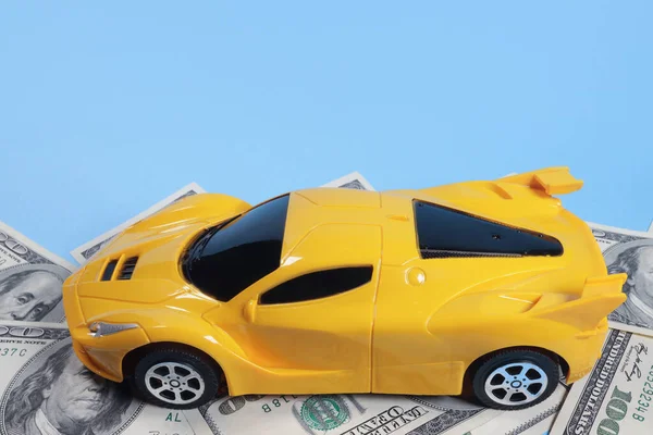 Toy car on dollar bills, concept of content auto insurance, repair, checkup