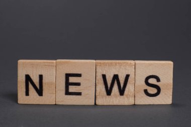 Gri arkaplandaki ahşap harflerden haberler.