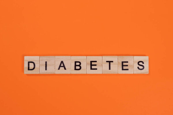 Слово диабет из деревянных букв на оранжевом фоне
