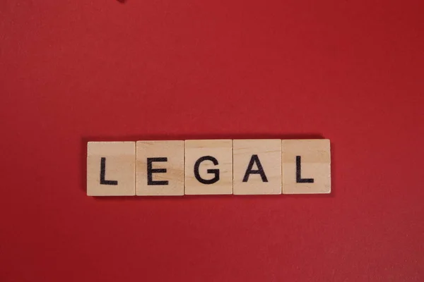 Word Legal from wooden letters on red background