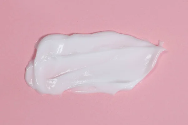 Smear of body or face cream on pink background
