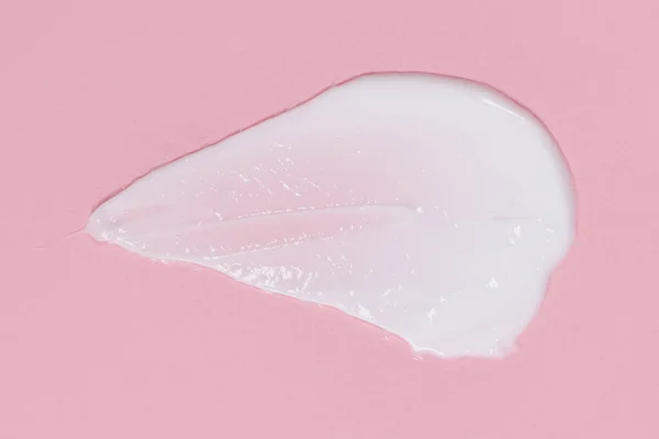 Face or body cream smeared on pink background