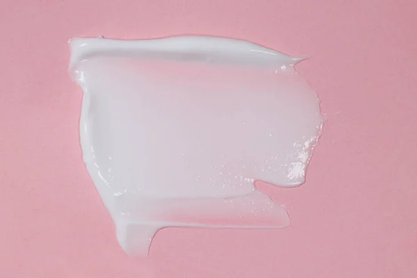 Face or body cream smeared on pink background