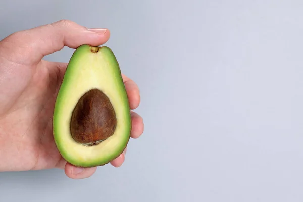 Hand Hält Eine Avocado Auf Grauem Hintergrund — Stockfoto