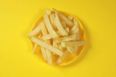Patates kızartması, sarı arka planda izole edilmiş bir tabakta kızarmış patates.