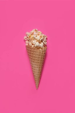 Tatlı karamelli patlamış mısır, pembe arka planda dondurmalı waffle fincanı. Dikey Yönlendirme