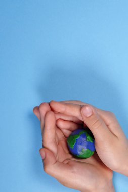 Çocuk eli, plastik gezegen Dünya 'yı tutuyor, ekoloji kavramı. Dikey Yönlendirme