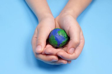 Çocuğun eli plastik gezegen Dünya 'yı tutuyor, ekoloji kavramı