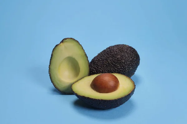 stock image avocado hass with a stone on a blue background, the concept of proper nutrition