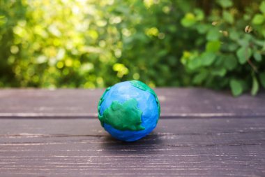 Yeşil bitkilerin arka planına karşı tahta bir yüzey üzerinde plastik gezegen Dünya