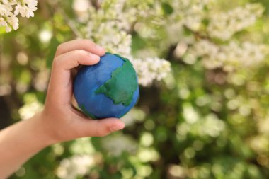 Çiçeklerin arkaplanındaki plastik gezegen Dünya çocukların ellerinde. Day Earth, çevre kavramını kaydet
