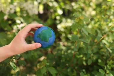 Çiçeklerin arkaplanındaki plastik gezegen Dünya çocukların ellerinde. Day Earth, çevre kavramını kaydet