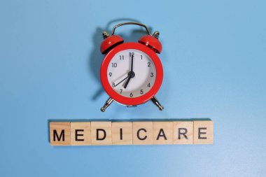 Medicare word and alarm clock on blue background clipart