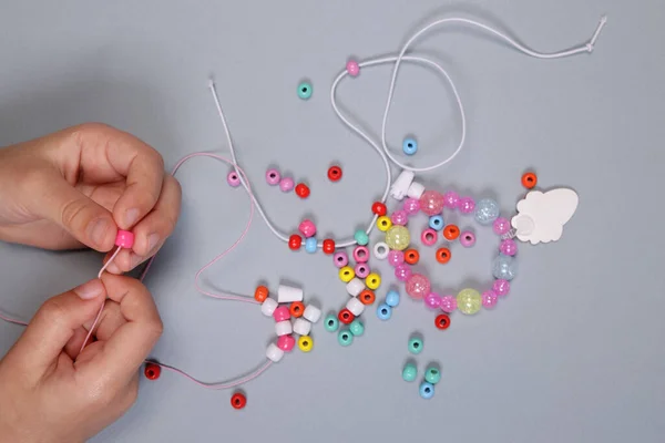 stock image Girl making a bracelet from colored beads close-up