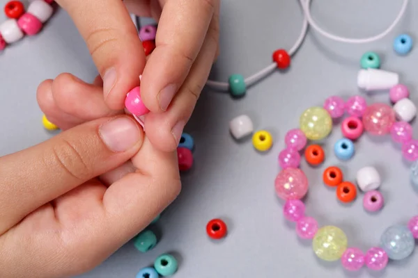 stock image Making a bracelet from colored beads, children's hands close-up