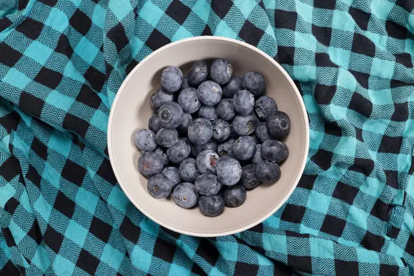 stock image Ripe blueberry in a bowl on a plaid blanket top view