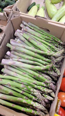 Süpermarkette kuşkonmaz ve domates kutularında taze sebzeler. Dikey Yönlendirme