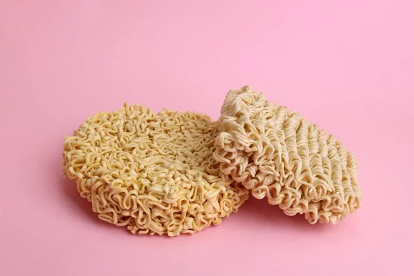 Dry uncooked instant noodles vermicelli on a pink background