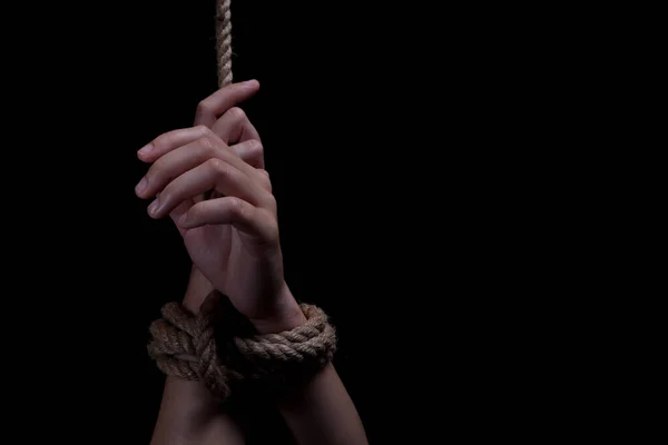 woman\'s hands tied with rope on black background, concept of domestic violence of the victim. copy space for text