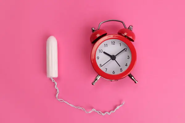 衛生的なタンポンとピンクの背景に目覚まし時計 重要な日の概念 — ストック写真