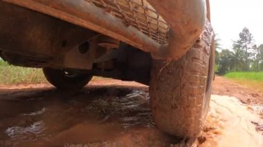 4x4 off road pikap tekerlekleri toprak bir yolda çalışıyor. Kirli yolda çamurlu, ıslak ve kuru çamurla hareket eden off-road kamyon tekerlekleri. Bakış açısına göre 4WD kamyon lastiği taşrada seyahat ediyor.