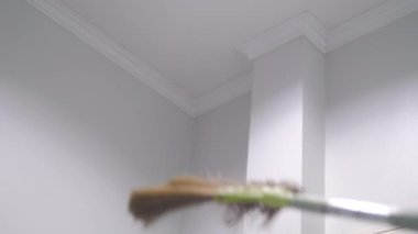 İnsanlar tavanı temizlemek için uzun süpürge kullanıyor.