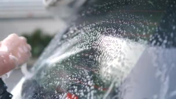 フォームシャンプーとウォータースプレーで車を洗う男の手 車のケアとクリーニング — ストック動画