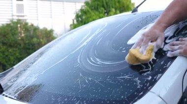 Arabayı köpük şampuan ve su spreyiyle yıkayan adamın eli. Araba bakımı ve temizlik
