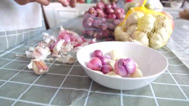 Yemek pişirmeye hazırlanan arpacık soğanlarını soyan kadın.