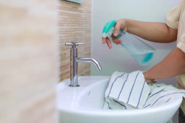 女性の手は浴室のシンクをきれいにするために布および水スプレーを使用します — ストック写真
