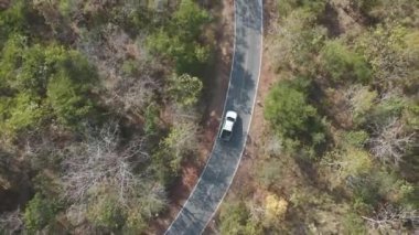 Drone 'un hava görüntüsü kurak mevsimdeki ıssız yolda arabayı sürüşün manzarası.