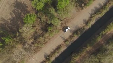 Drone 'un hava görüntüsü kurak mevsimdeki ıssız yolda arabayı sürüşün manzarası.
