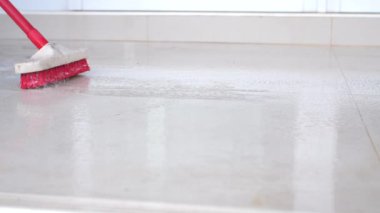 İnsanlar fayansları temizlemek için uzun saplı fırça kullanıyor.