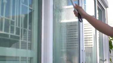 İnsanlar cam kapıyı su ve aletlerle temizliyorlar. Evde bakım kavramı.