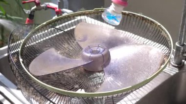 İnsanlar vantilatör bıçağını temizlemek için su püskürtüyor.