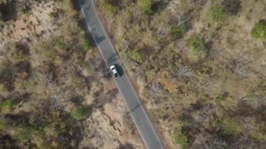 İnsansız hava aracı görüntüleri kırsal kesimde kurak mevsimde terk edilmiş bir yolda kamyonet sürerken görüntüler.