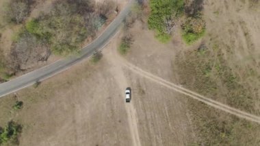 İnsansız hava aracı görüntüleri kırsal kesimde kurak mevsimde terk edilmiş bir yolda kamyonet sürerken görüntüler.