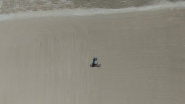 Drone videosu bir traktör cassava kurutma sahasına cassava yayıyor. Cassava un hazırlama süreci