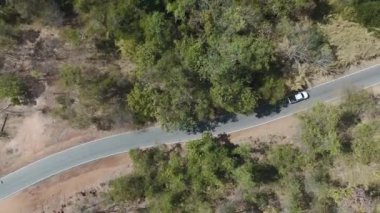 İnsansız hava aracı görüntüleri kırsal kesimde kurak mevsimde terk edilmiş bir yolda kamyonet sürerken görüntüler.