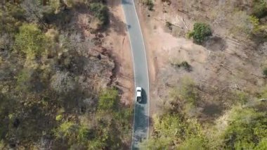 İnsansız hava aracı görüntüleri kırsal kesimde kurak mevsimde terk edilmiş bir yolda kamyonet sürerken görüntüler.