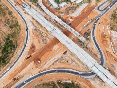 Vinç işçileri, traktörler ve kepçeler tarafından kavşağın üzerine beton köprü inşa edilmeden önce inşaat alanı