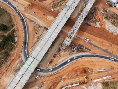 Vinç işçileri, traktörler ve kepçeler tarafından kavşağın üzerine beton köprü inşa edilmeden önce inşaat alanı