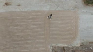 Drone videosu bir traktör cassava kurutma sahasına cassava yayıyor. Cassava un hazırlama süreci