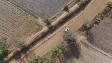 Kırsal bir yolda kırsal araziden geçen bir kamyonetin hava aracı görüntüsü. Doğada seyahat, ulaşım ve özgürlüğün manzaralı görüntüsü
