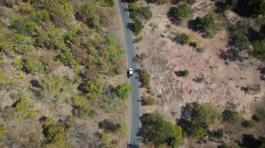 Kırsal bir yolda kırsal araziden geçen bir kamyonetin hava aracı görüntüsü. Doğada seyahat, ulaşım ve özgürlüğün manzaralı görüntüsü